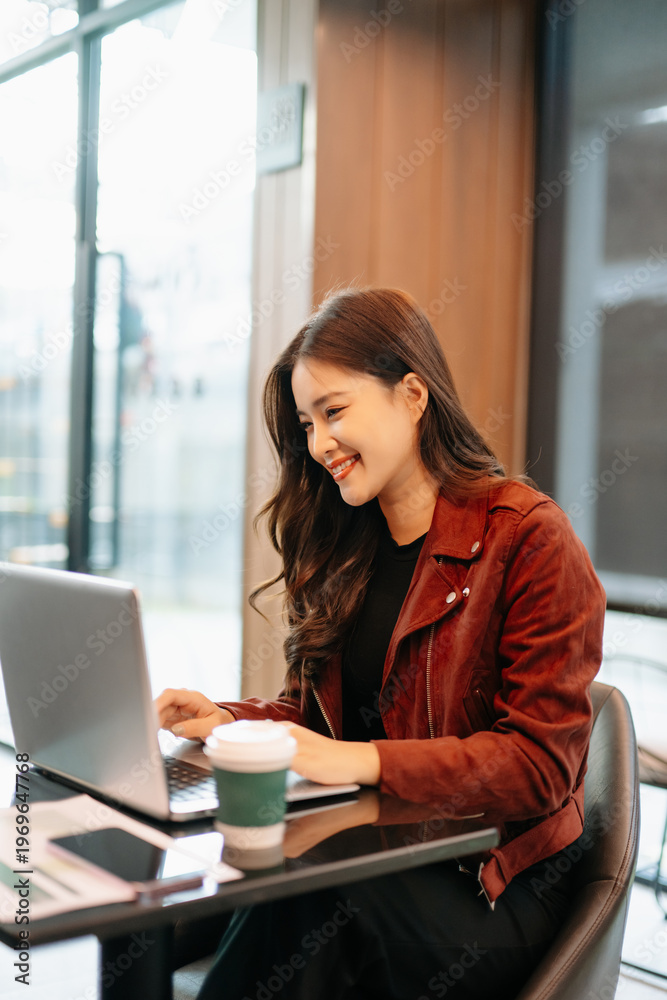 Obraz premium Asian Businesswoman Analyzing Financial Data Reports in Modern Cafe