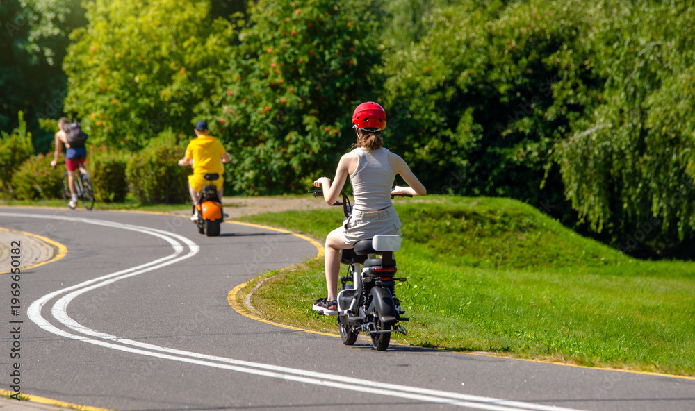 Obraz premium Girl rides an electric scooter in the summer Park