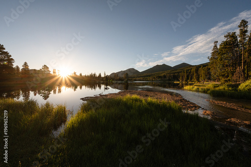 Sunrise reflecting on mountain lake with double sunburst in summer