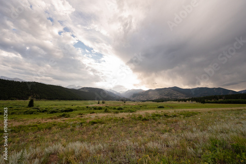 Rockies wilderness landscape with dark clouds and green meadow