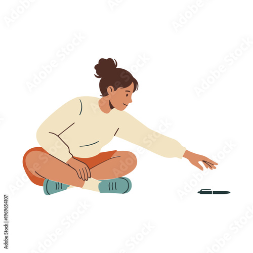 A woman sits on the floor and picks up a pencil.