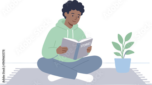 A person reading a book while sitting on a floor next to a plant
