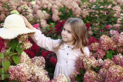 Adorable Little Girl in a Garden of Hydrangeas with a Hat, exploring Nature s Beauty and Wonder.