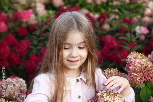 Charming Little Girl Surrounded by Hydrangeas in a Lush Garden, Lost in Thought and Wonder.