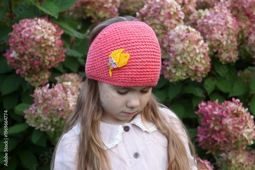 Adorable Girl Wearing a Crochet Headband with Hydrangeas in the Background - Outdoor Portrait.
