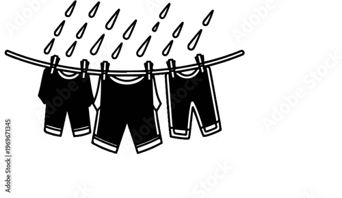 Three dark garments hang on a clothesline as rain falls