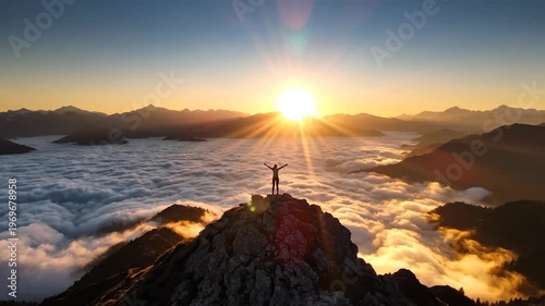 Silhouette of person on mountain peak above clouds with arms raised celebrating success at sunrise