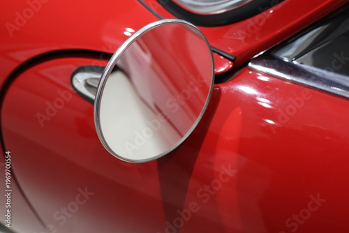 Side mirror of a red car captured in close‑up, highlighting sleek automotive design, glossy paint, and modern vehicle details. Clean composition suitable for transportation themes, car advertising, 