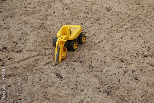 Plastic toy excavator in a sandbox, symbolizing childhood play, construction toys, and outdoor activities for kids. Bright colorful vehicle designed for boys’ imaginative play,krakow, poland, may 2026