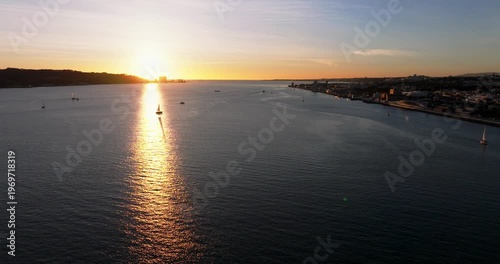 Wide aerial sunset shot of Lisbon Portugal 25th April red suspension bridge famous iconic landmark over water