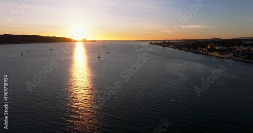 Sunset skyline view of Lisbon Portugal 25th April red suspension bridge famous iconic landmark and river