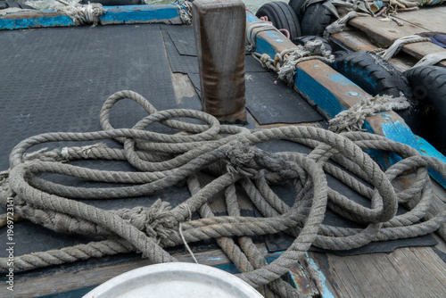 Canvas-taulu Coiled rope rests on a boat deck beside wooden pilings