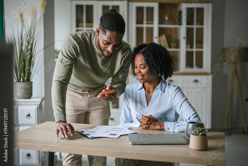 Foto Couple managing home finances using phone and paperwork