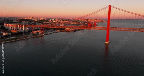 Golden sunset over Lisbon Portugal 25th April red suspension bridge famous iconic landmark above Tagus waters