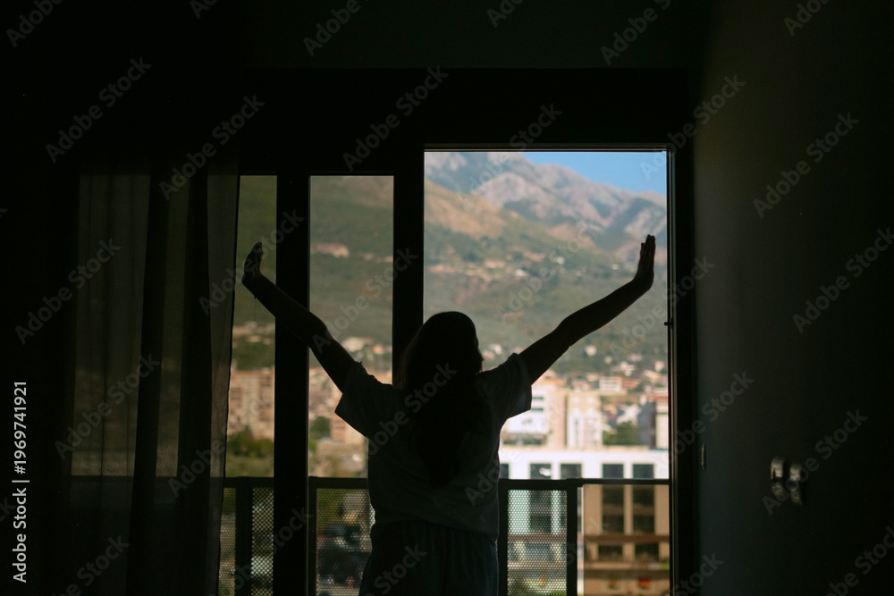 Fototapeta premium Woman in pajamas waking up in the morning stretching and opening window with mountain view calm routine cozy atmosphere natural light