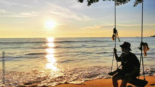 Silhouetted person on swing at beach during golden sunset
