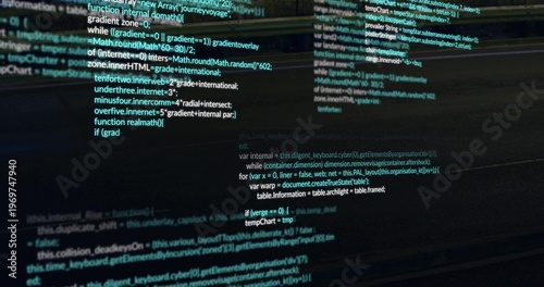 Showing syntax-highlighted code columns scrolling on widescreen monitor at desk, with reflections
