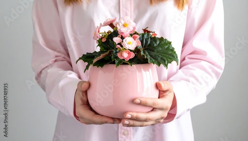 A person in a pink shirt holds a rounded pink planter filled with vibrant pink and green flowers