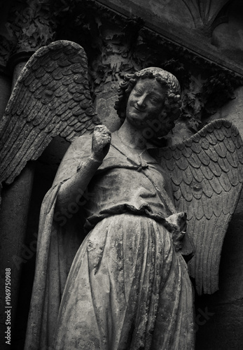 Gentleness. Smiling angel looking at you from facade of Notre Dame Cathedral of Reims, France. Black white historic photo. 