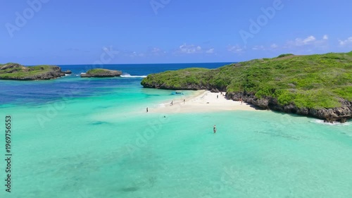 Aerial view of people swimming and walking on a white sandbar surrounded by turquoise water and green rocky islands at Watamu Beach, Kenya.