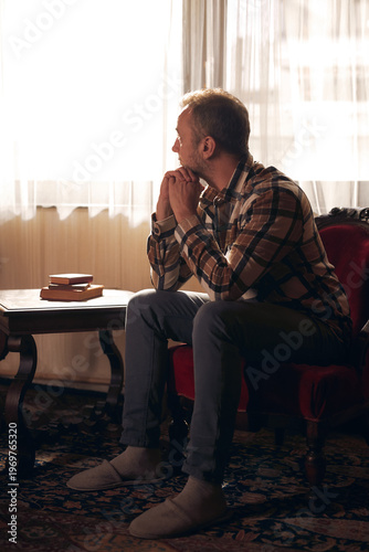 Man with depression sitting on a chair at home.