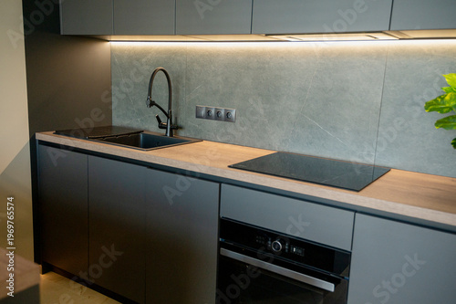 The contemporary kitchen features a black induction cooktop, built-in oven