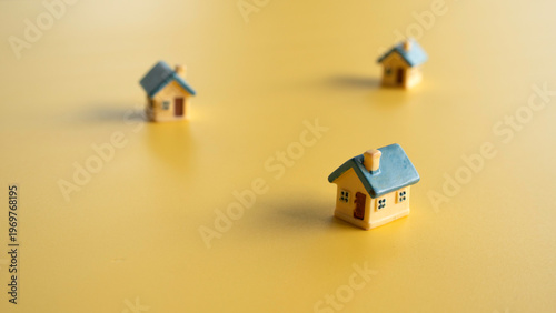 Fotografie High angle view of scattered miniature houses on yellow background representing suburban development and neighborhood planning