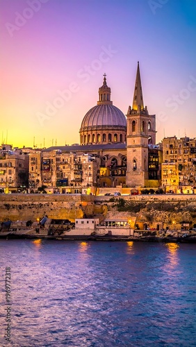 A picturesque cityscape at twilight with a prominent church dome and tower, reflecting the soft hues of the sky in the water