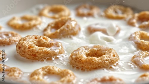 Close-up macro lens view of cereal rings floating in milk with bubbles, showcasing the texture and color of the cereal in a shallow dish setting