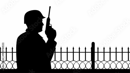 Silhouette of a security guard in uniform wearing a helmet holding a pistol and a radio standing guard behind a spiked metal fence with circular decorative elements during daytime