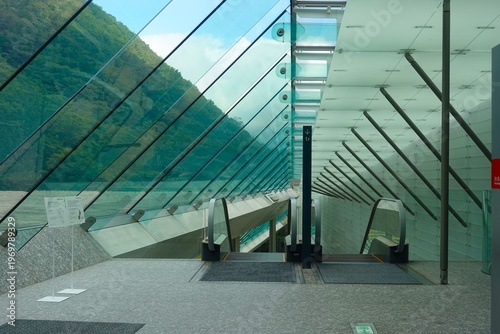 Obraz na plátne Modernist museum entrance with glass canopy and escalators overlooking mountain