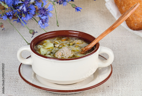 Soup with meatball  is on rural table.