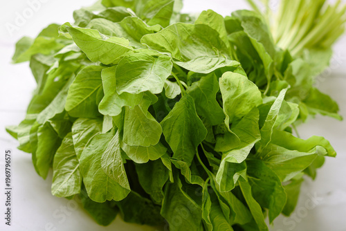 Closeup of fresh spinach leaves bundled together, showing vibrant green color and natural texture.