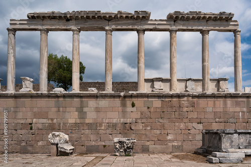 Ancient Temple of Trajan ruins with majestic columns and stone wall at Pergamon Acropolis, Bergama, Izmir, Turkey under a cloudy sky