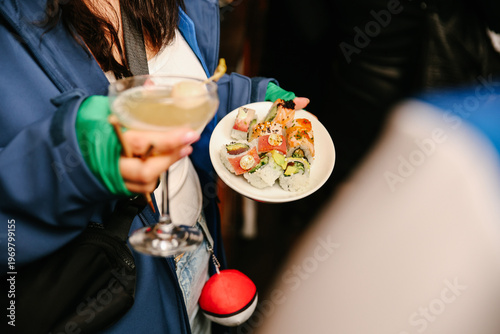 Schilderij op canvas Horizontal Close-up of an Event Guest Holding a Plate of Assorted Sushi and a Ma