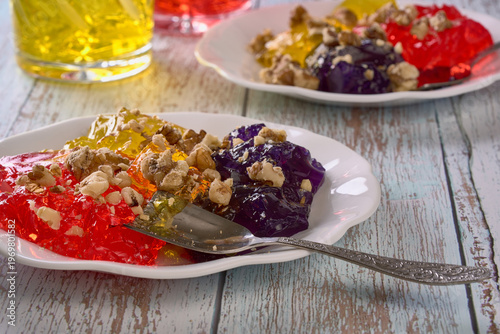 Brightly colored jelly desserts sit on plates with chopped nuts on top, ready to be enjoyed at a family gathering