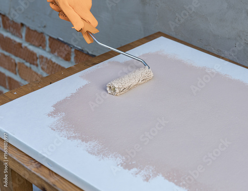 Gloved hand applies paint with a roller