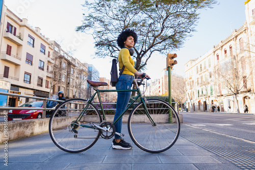 Woman standing with bicycle in city looking away