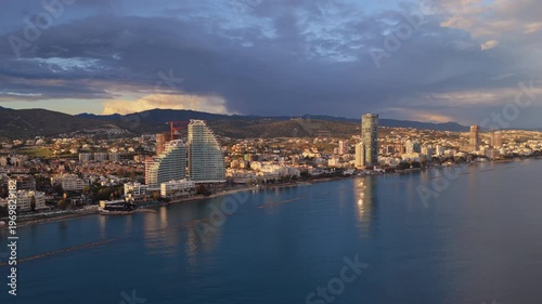 Aerial drone view of Limassol coastline showing modern architecture, residential buildings and calm Mediterranean waters under soft evening light