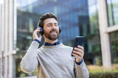 Fényképezés Close-up photo of a young man wearing headphones outside and listening to music