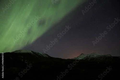 Green sheet of aurora borealis covering half of a deep starry sky Iceland