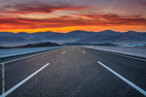 Straight asphalt highway through a mountain valley at sunrise
