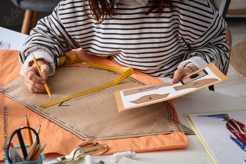 Bild auf Leinwand Female fashion designer making pattern at table in studio