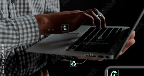 Male holding laptop lefthand, typing righthand in studio, causing eco overlays shifting: chart, CO2