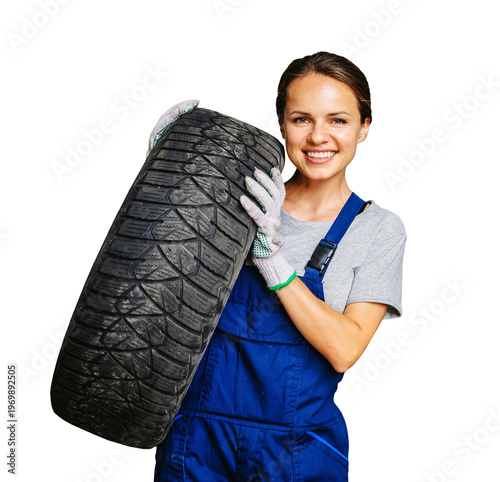 Smiling female auto mechanic in blue overalls holding a car tire, isolated on transparent background.