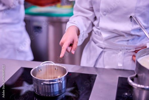 Küchenchef gibt Anweisungen: Finger zeigt auf einen kochenden Topf.