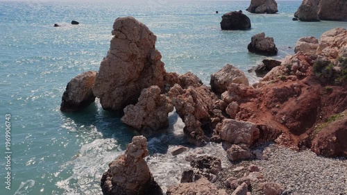 Aerial drone view of scenic coastal rock formations rising from the turquoise waters near Aphrodite's Rock in Cyprus, a famous natural landmark