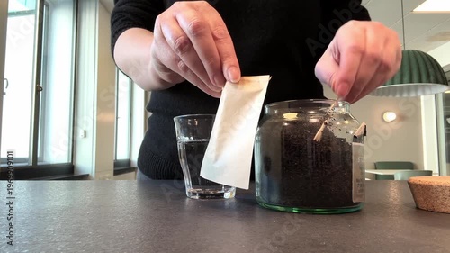 Close up female hand brewing tea bag in transparent mug, cozy lifestyle