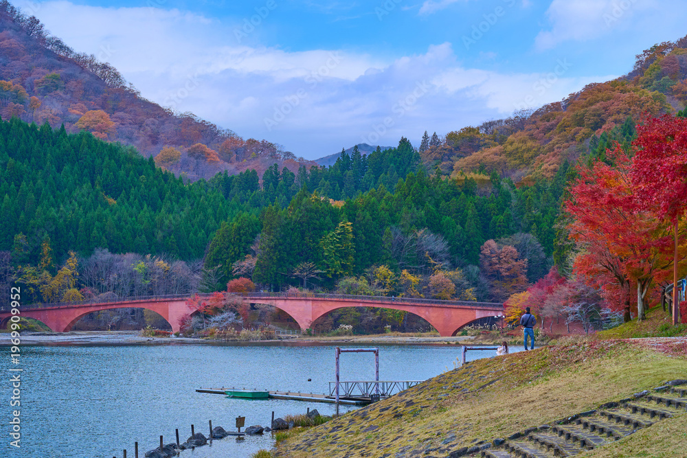 Fototapeta premium 秋の群馬県安中市の坂本ダムの赤い夢のせ橋を見る