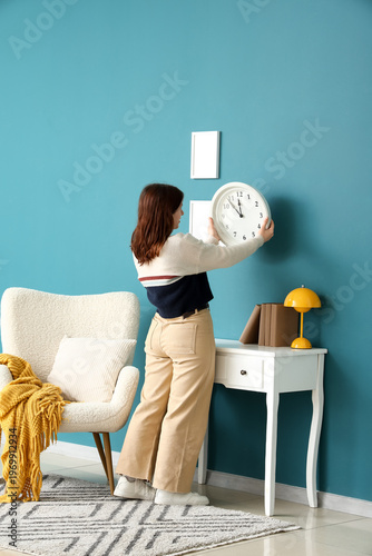 Young woman hanging clock o...